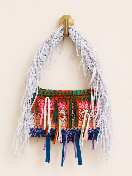 Colorful woven bag with fringe on a beige background