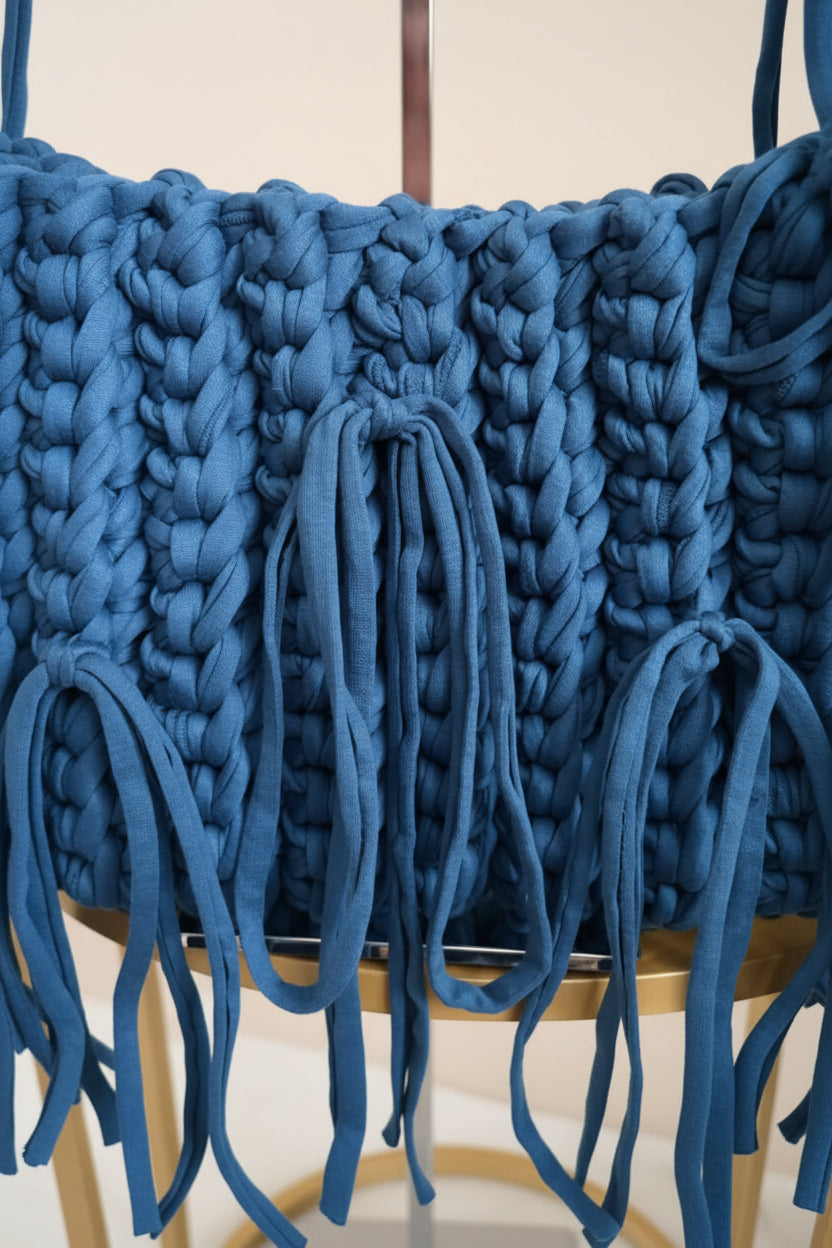 A close-up of a chunky, oversized chunky crochet bag in blue