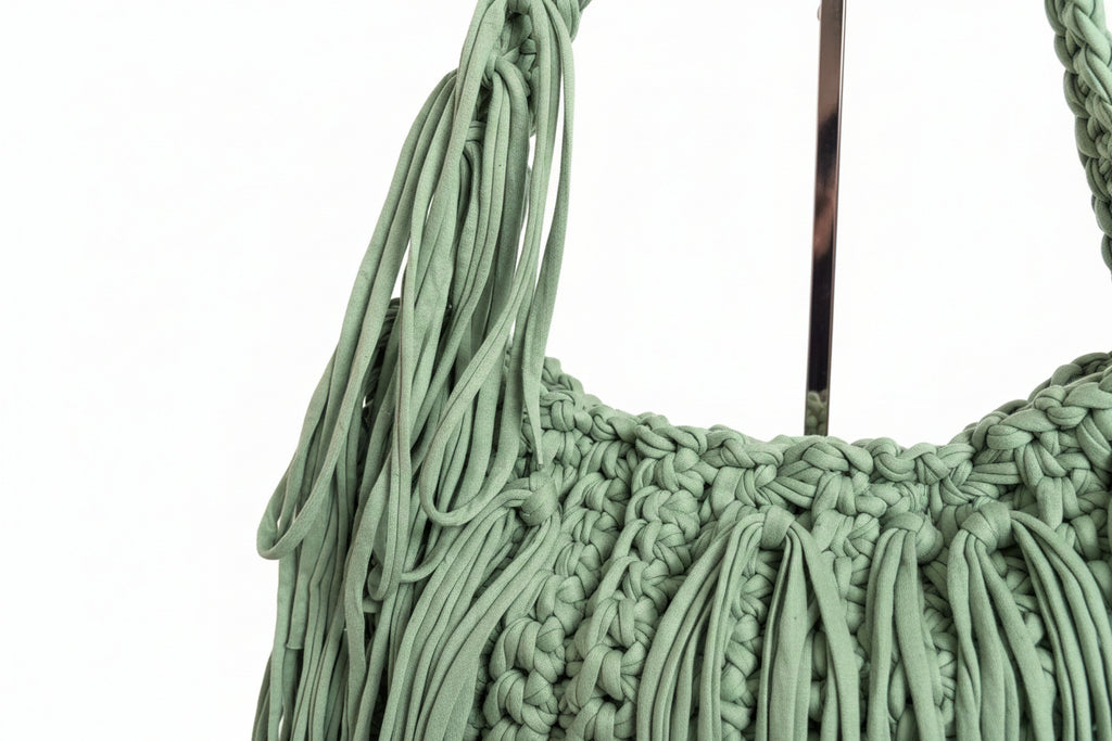 A close-up of a sage green crochet woven bag 