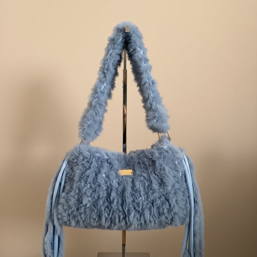 A light blue fuzzy faux-fur shoulder bag with a matching strap