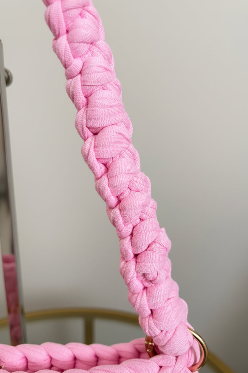 A close-up of a light pink braided fabric strap
