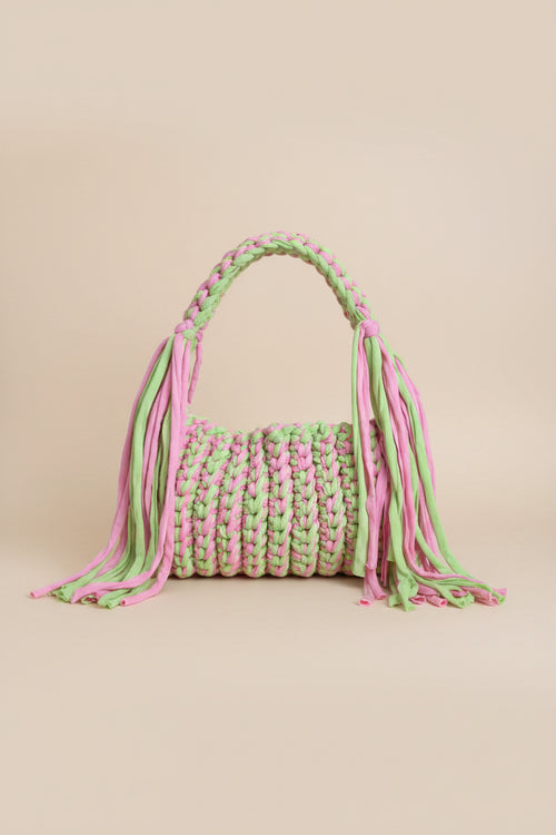A close-up of a chunky braided crochet bag in alternating pastel pink and light green yarn
