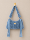 Blue textured handbag with tassels on a beige background