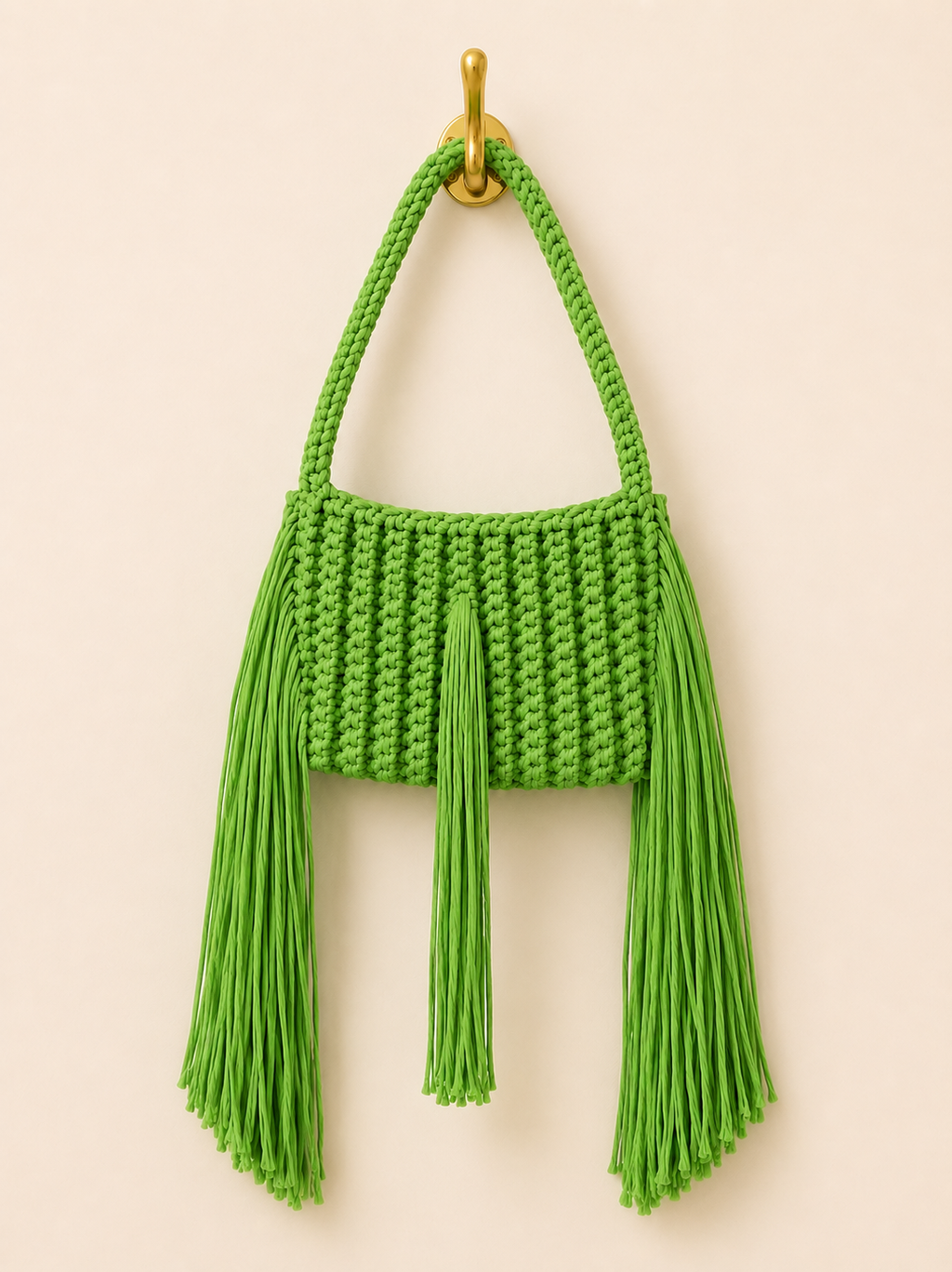Green knitted handbag with tassels on a beige background