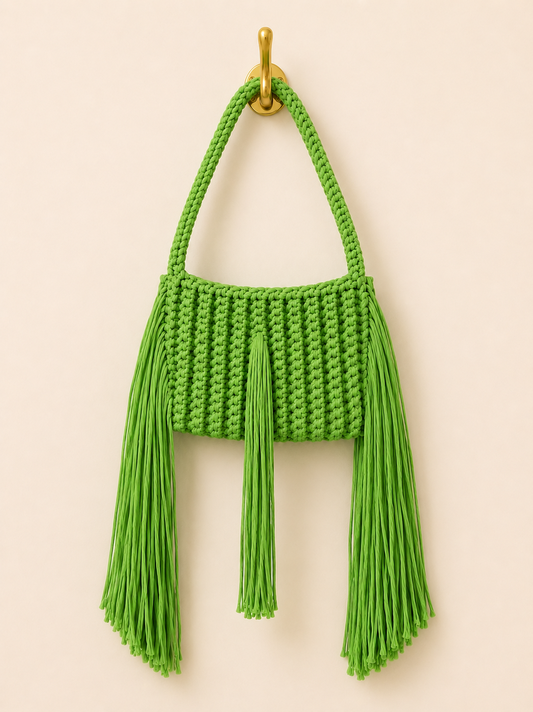 Green knitted handbag with tassels on a beige background